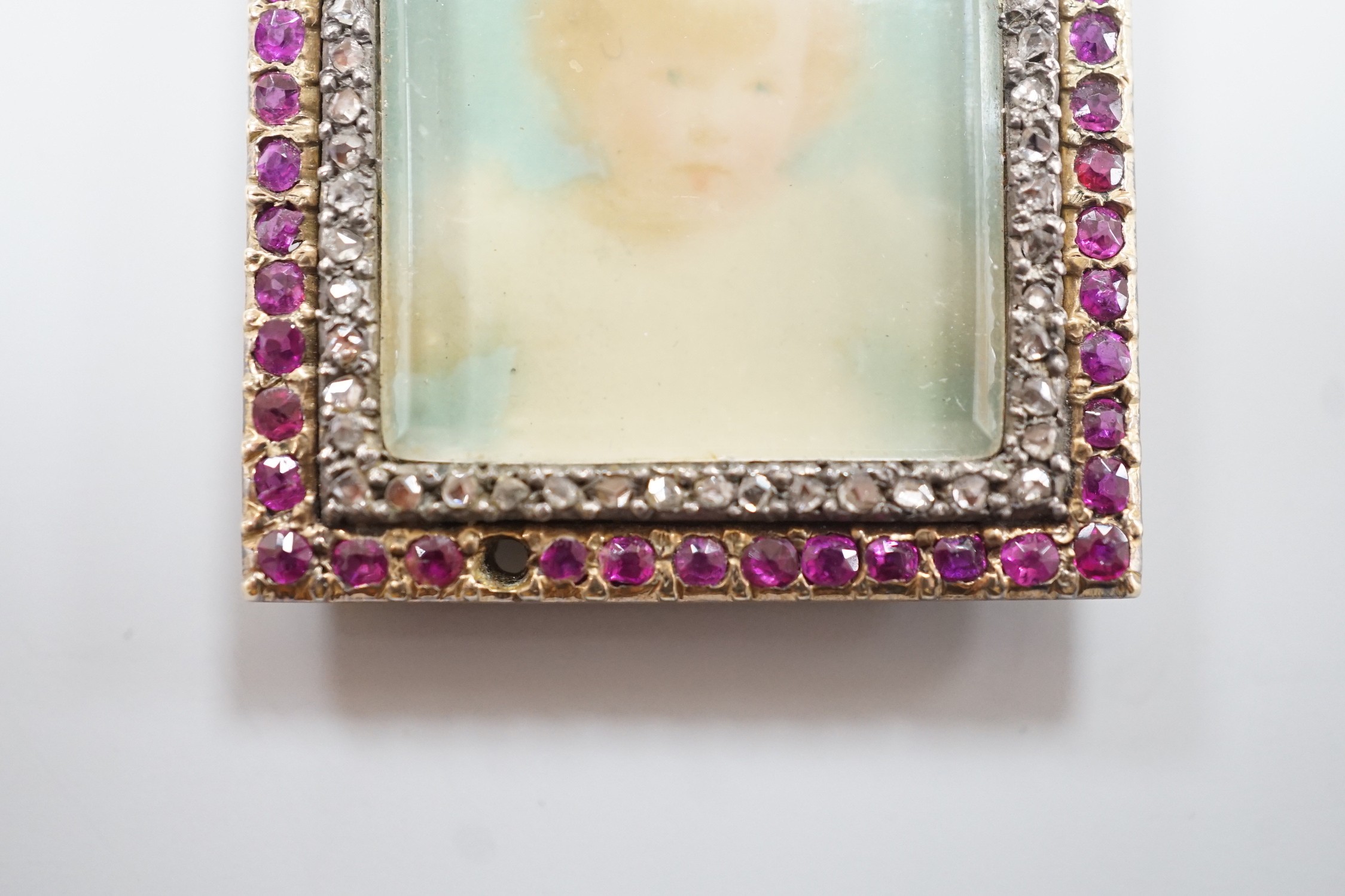 An early 20th century yellow metal, ruby and diamond mounted portrait pendant, 34mm (two rubies missing), on a 9ct chain